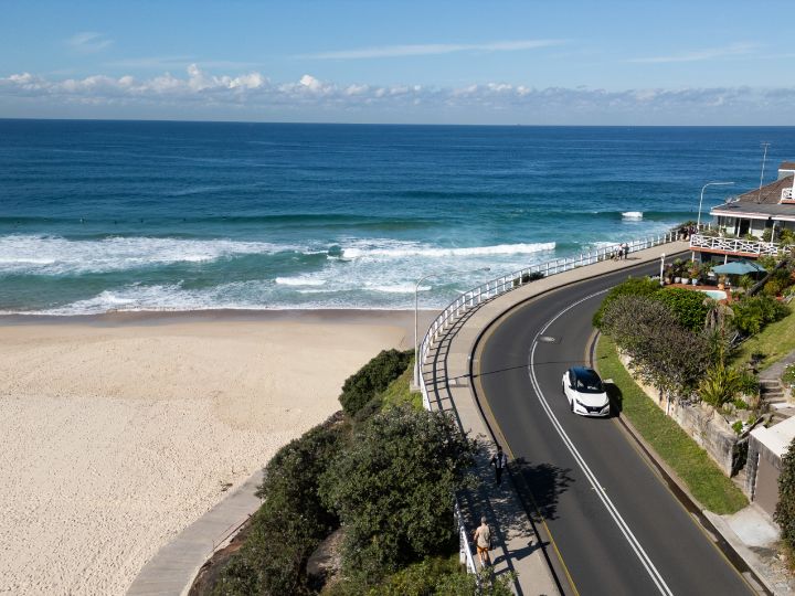 Nissan Leaf driving down a road next to a beach in Australia