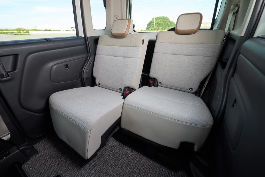 Rear seats of the new Nissan Roox kei car. Two separate greige seats are placed side by side, each with a headrest. The view outside the window is visible.