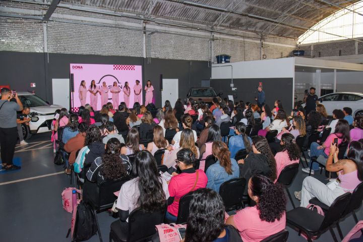 A influenciadora Vittória Gabriela, dona do canal Dona do Meu Destino, e suas instrutoras em um palco com o logotipo da Nissan ao fundo, diante das cerca de 100 alunas