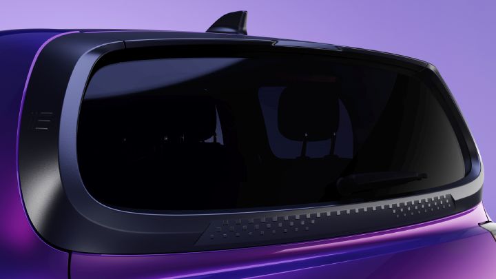 Fotografia que mostra a parte traseira de um veículo roxo com um grande vidro escurecido. Os acabamentos pretos elegantes, a aleta no tejadilho, o limpa-vidros traseiro e o painel de ventilação texturado realçam o design aerodinâmico contra um fundo cor de lavanda.