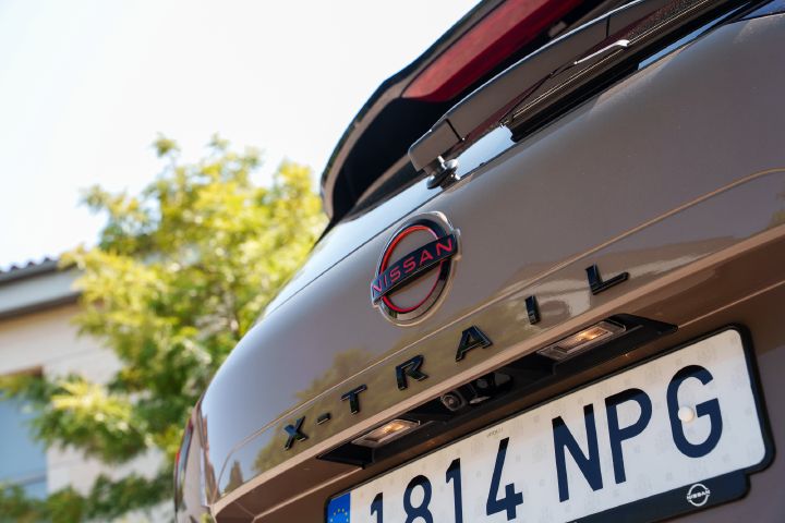 Detailansicht auf das Logo des Nissan X‑Trail am Fahrzeugheck von schräg unten