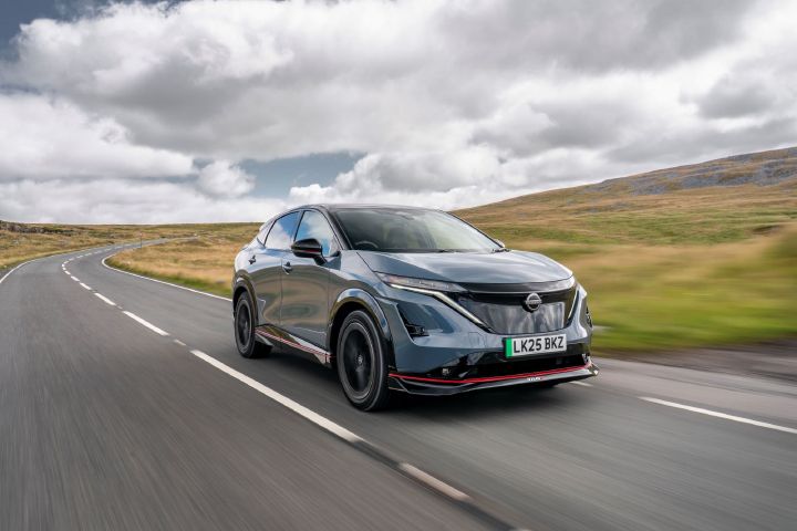 A grey 2025 Nissan Ariya NISMO drives along a country road in the sunshine