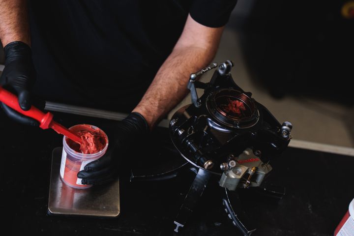 Ein Nissan Mechaniker entnimmt eine rote Paste mit einem Spatel aus einer Dose, Nahaufnahme