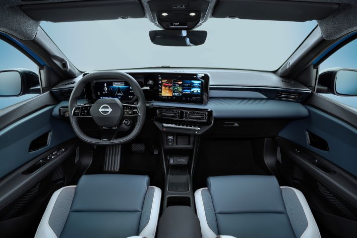 rear seat POV of full dashboard cockpit showing front seats, steering wheel, rear view mirror, infotainment and side mirrors