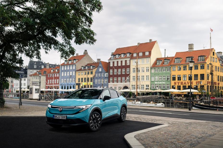 Skrå frontvinkel af Nissan LEAF med farverige, klassiske bygninger i København i baggrunden.