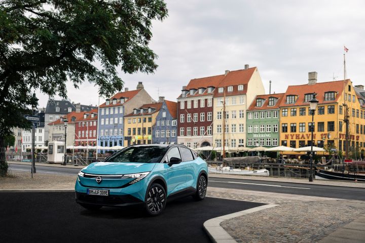 Skrå frontvinkel af Nissan LEAF med farverige, klassiske bygninger i København i baggrunden.