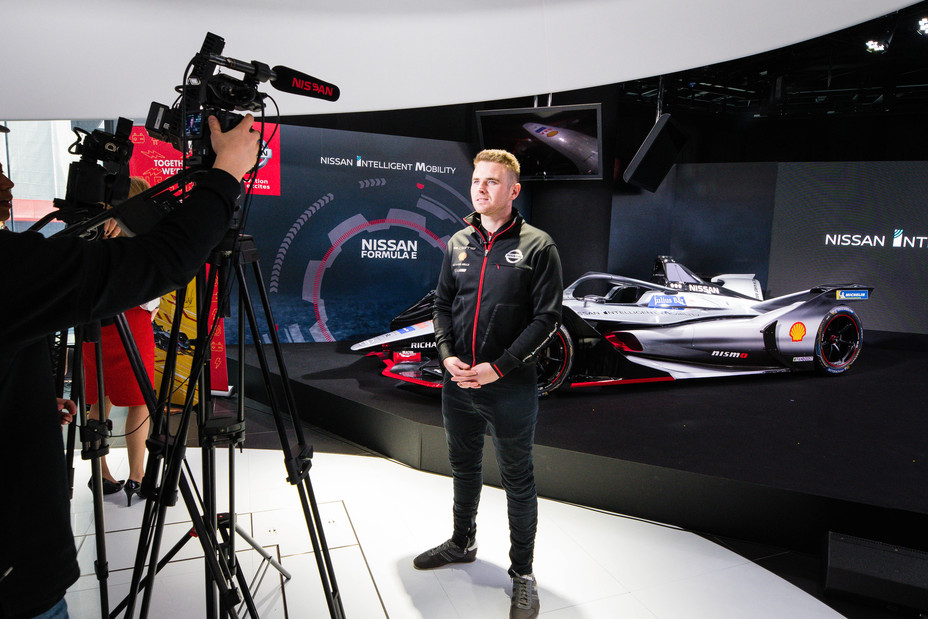 A race car driver speaking to the press at an event.