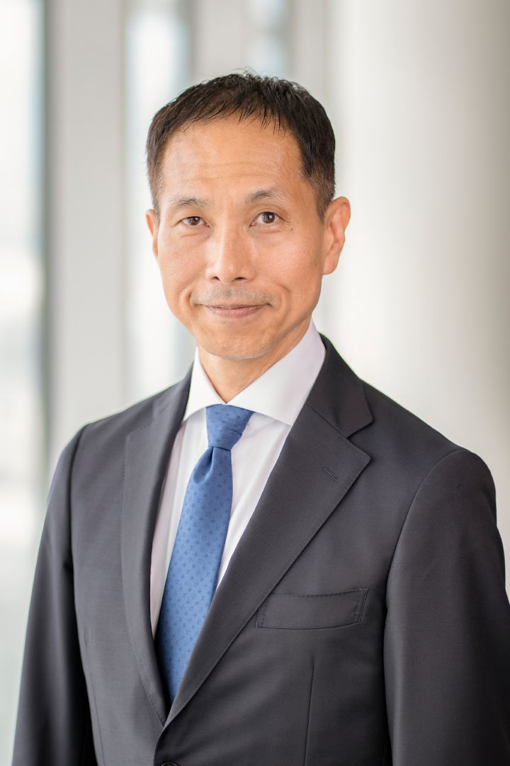 Portrait of Toru Ihara with navy blue suit, tie and NISSAN corporate pin (smiling)