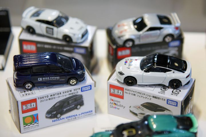 Cinco miniaturas de carros da Nissan apoiadas em suas caixas