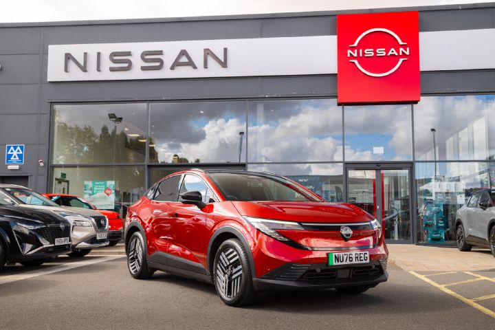 Front three-quarter view of a red Nissan LEAF outside a Nissan showroom