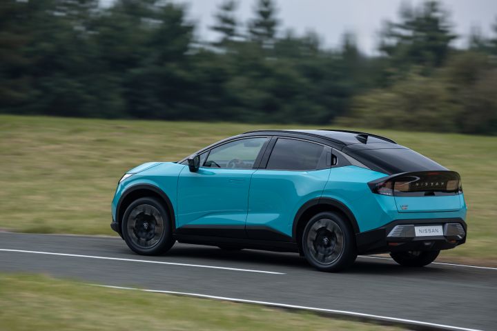 Vue latérale arrière d'une nouvelle Nissan LEAF en mouvement, de couleur bleu turquoise, devant un espace vert avec des arbres en arrière-plan.