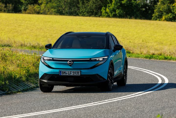 Nissan LEAF navigating a winding rural road bordered by green fields
