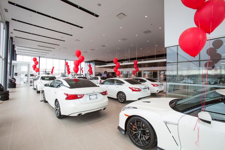 Intérieur d'une concession présentant des voitures blanches avec des ballons rouges.