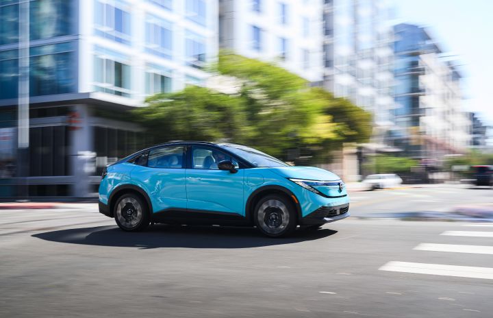 Front right 3/4 view of the 2026 Nissan LEAF driving on a city street.