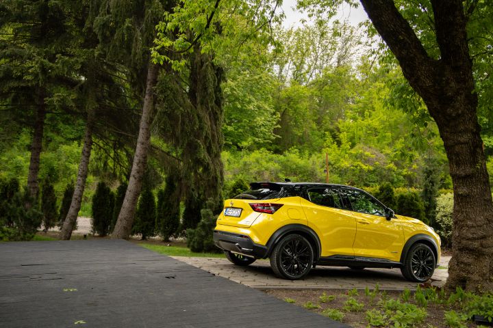 Stojący żółty Nissan Juke (widok z boku) na tle zieleni