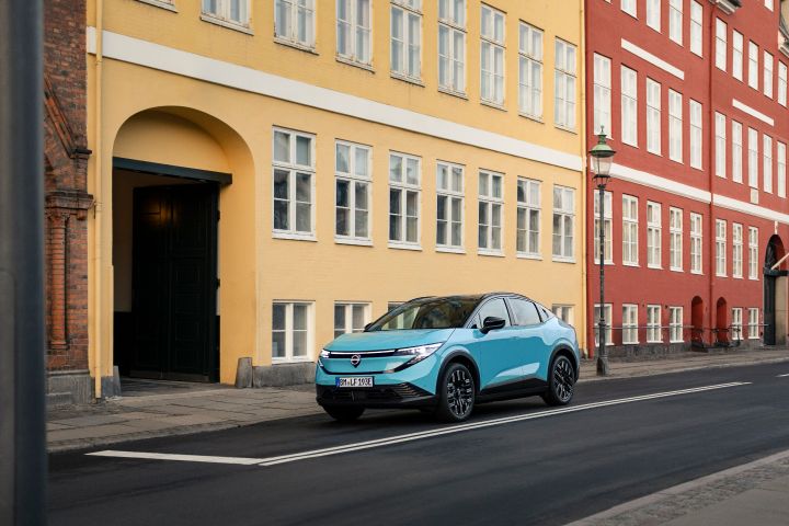 Vor einem beigen Gebäude parkt ein türkiser Nissan LEAF im Zentrum von Kopenhagen, 3/4 Frontansicht