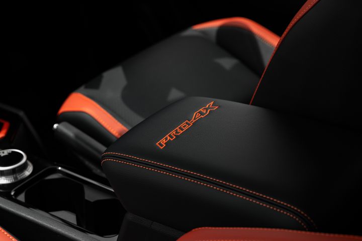 2026 Nissan Navara PRO-4X finished in Boulder Grey focusing on the PRO-4X armrest lid, orange stitching and front seat cushion with red edging.