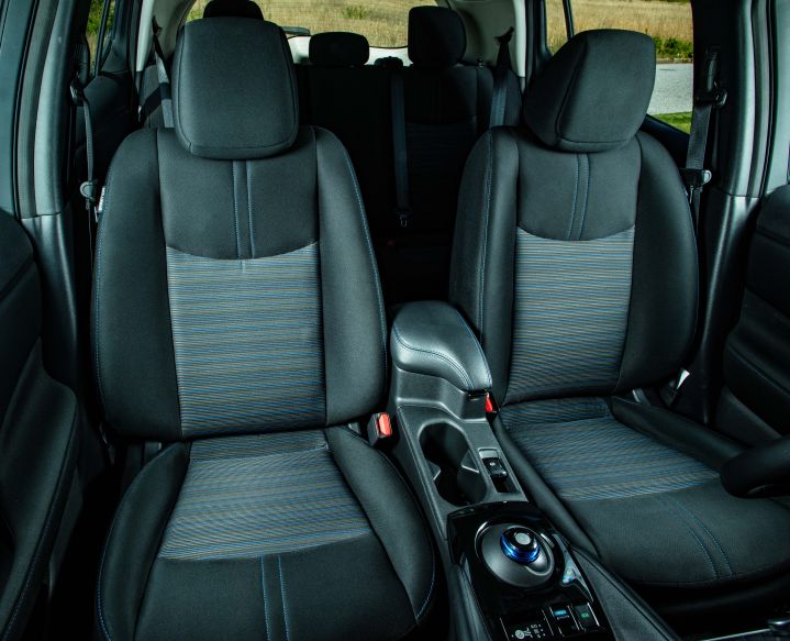 The dark cloth driver, passenger seat, and middle console inside the 2025 Nissan LEAF.