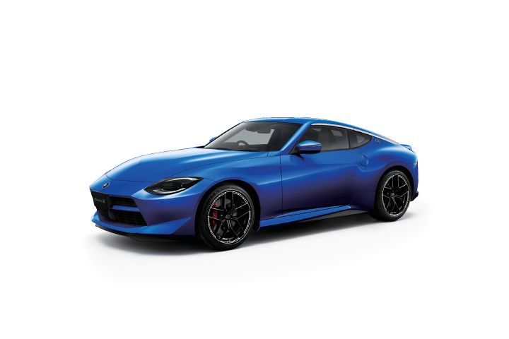 Blue Fairlady Z photographed in a light gray studio setting. The vehicle is shown in a front-left three-quarter view, with the front end facing toward the left side of the image. The long-hood, short-deck sports car proportions are emphasized, while black alloy wheels and red brake calipers add contrast. The clean, neutral background highlights the vivid blue body color and sculpted exterior design.