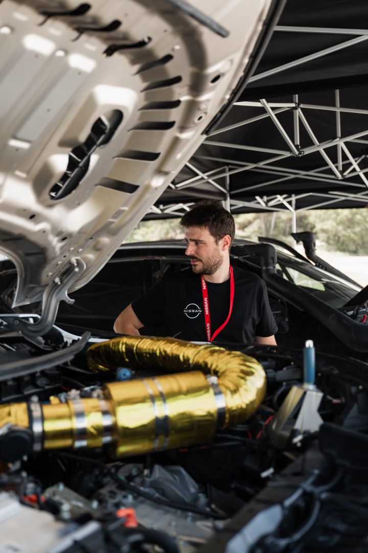 Hinter der geöffneten Motorhaube des Nissan X‑Trail Rennwagens inspiziert ein Nissan Ingenieur während der Baja Aragon Rallye 2024 den Motorraum