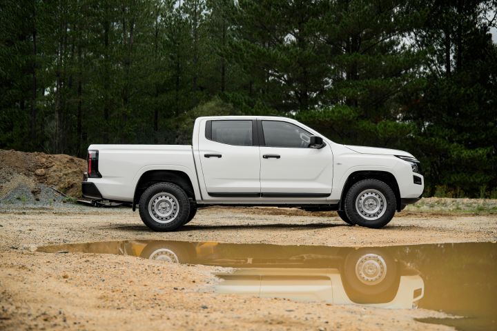 2026 Nissan Navara SL dual cab ute finished in Alpine White displayed in a full side profile on gravel, highlighting the dual cab body, tray length and puddle reflection.