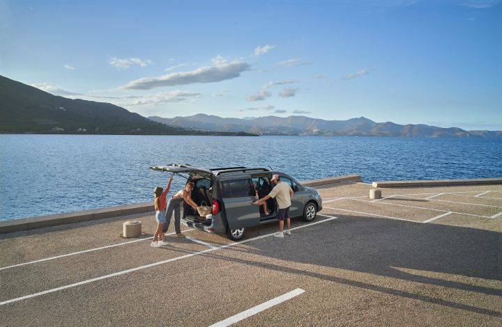 Nissan TOWNSTAR Evalia EV geparkeerd aan het water, achterklep en schuifdeur open, drie mensen erbij