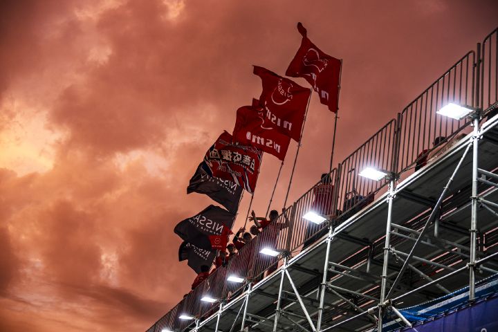 Nismo Fahnen auf der Rückseite der Tribüne des Nissan Formula E Teams beim E-Prix in Tokio vor rotem Abendhimmel.