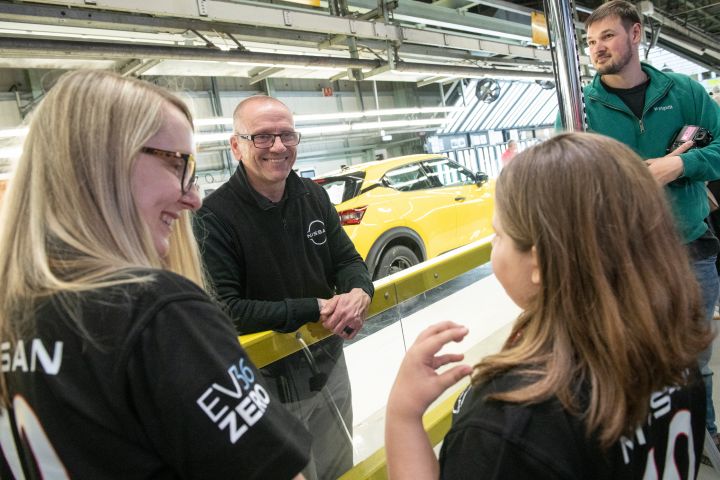 A school child talking with a Nissan worker on the production line, with Nissan Qashqai on the production line visible in the background.