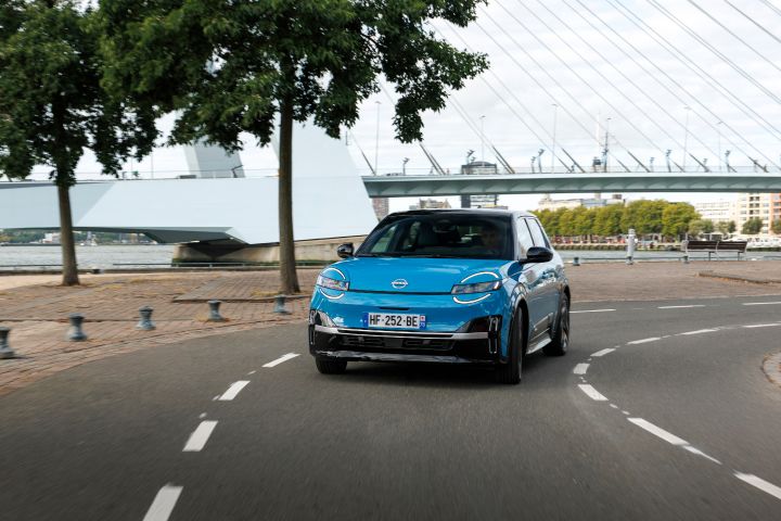 Ein blauer Nissan Micra biegt um eine Kurve und fährt dem Betrachter entgegen