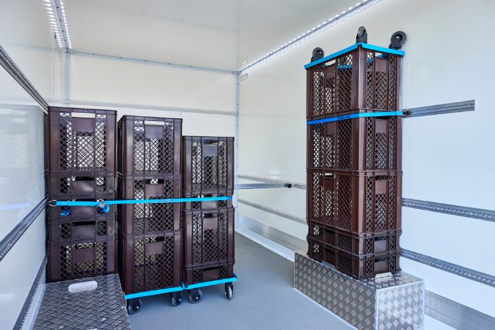 Braune Bäckerkörbe im Inneren des Nissan Interstar-e mit Bäckereikoffer, die mit Hilfe von blauen Gurten und einer metallenen Querstrebe gesichert werden
