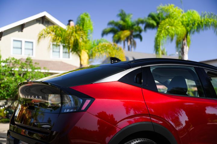 Close up of the rear half of the 2026 Nissan LEAF parked in front of a house and palm trees.