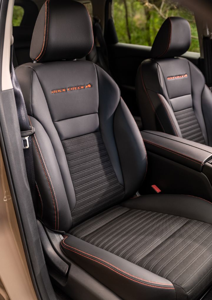 The black passenger interior seat with red stitching that sits inside the 2025 Nissan Rogue rock creek.