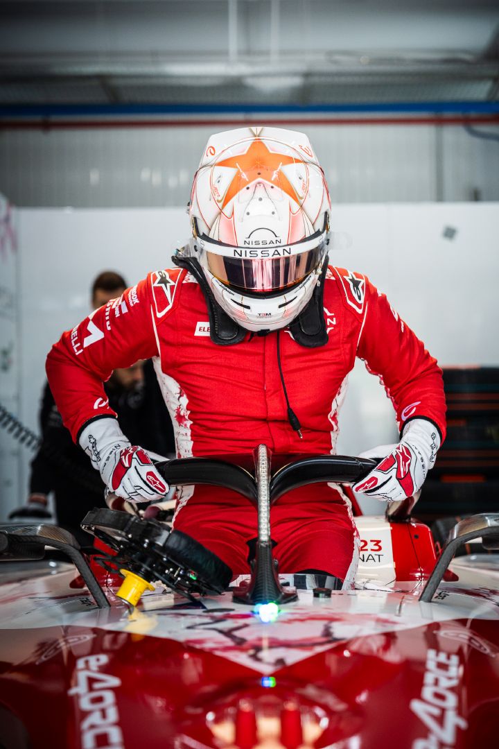 Norman Nato getting into the #23 car with his helmet and red team race suit on.