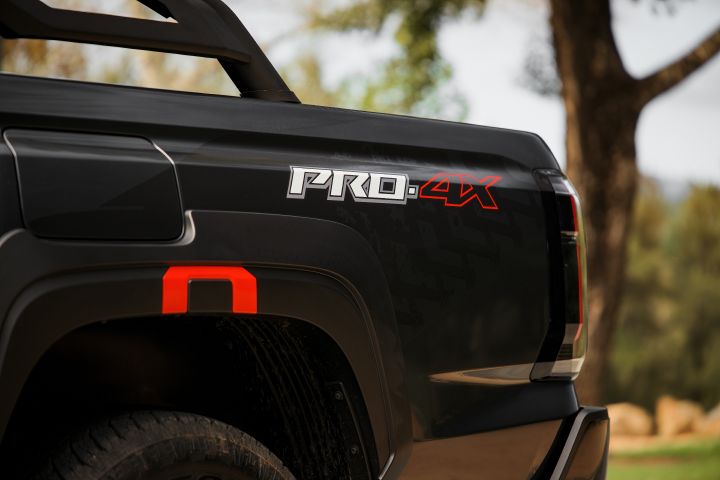 2026 Nissan Navara PRO-4X finished in Boulder Grey showcasing the rear tub-side PRO-4X decal, sports bar and wheel-arch cladding with red detail.