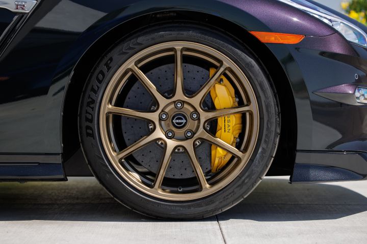 Close-up of the tire and wheel on the 2024 GT‑R T-spec Takumi, the rim is gold, the brake and even brighter gold.