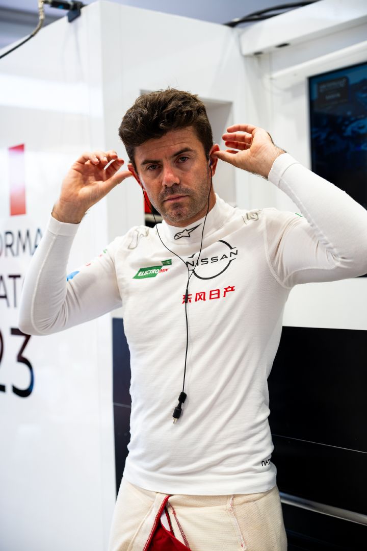 Porträtfoto von Nissan Formel E Fahrer Norman Nato, der in seinem weißen Unterhemd seine Ohrhörer einsetzt.