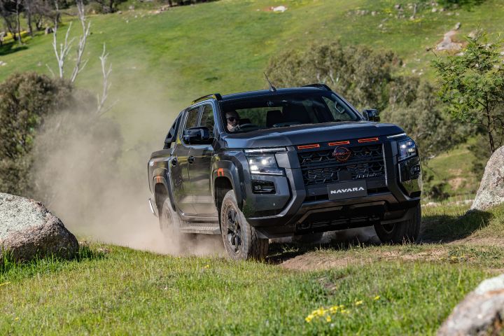 Dynamic front ¾ exterior image of a 2026 Nissan NAVARA PRO-4X off-road driving through grass