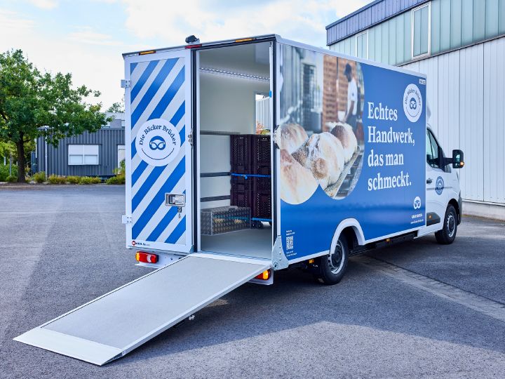 3/4 Heckaufnahme vom Nissan Interstar-e mit Bäckereikoffer, eine Hälfte der Hecköffnung ist als schräg zum Boden abfallende Verladerampe ausgeklappt