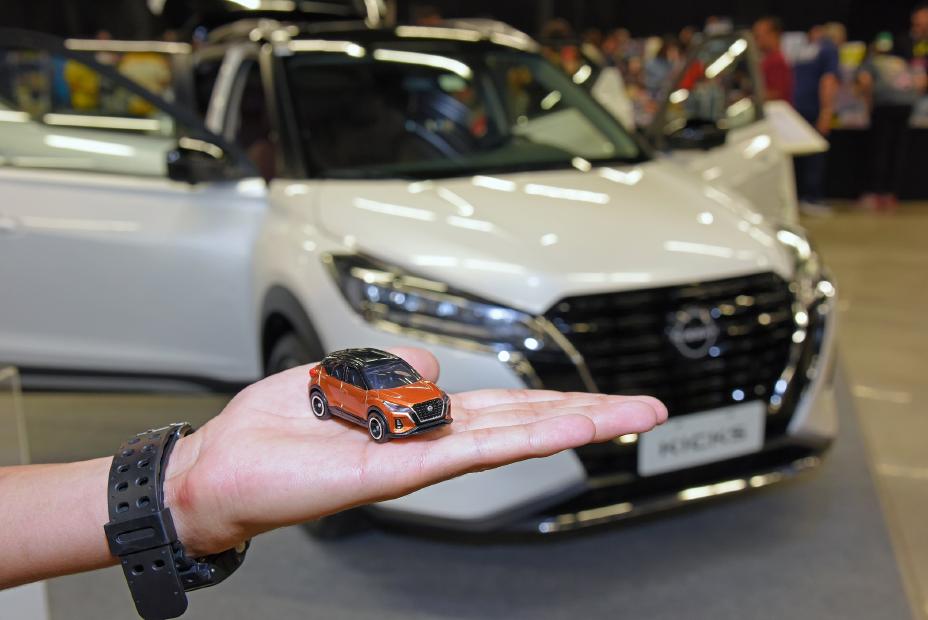 Versão miniatura do carro Nissan Kicks, ao fundo uma versão em tamanho real do modelo