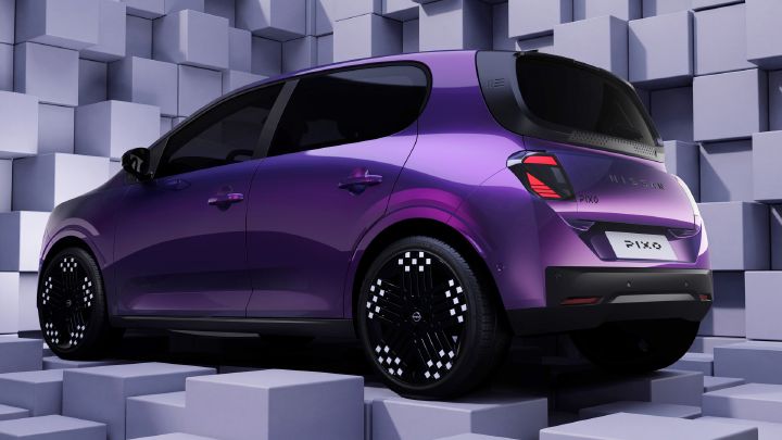 Studioaufnahme eines violetten Nissan PIXO Elektro-Fließheckmodells in Dreiviertel-Rückansicht. Ein geometrischer, weiß-grauer Würfelhintergrund, dunkel getönte Scheiben, gemusterte Leichtmetallfelgen, kunstvoll inszenierte Beleuchtung sowie gut sichtbare Nissan PIXO- und Modellembleme unterstreichen das Fahrzeugdesign.