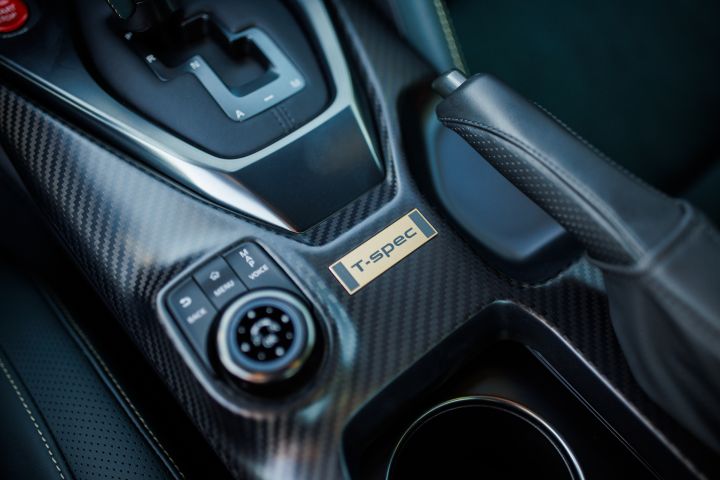 Close-up of the gold T-spec badge below the gear shift area and above the E-brake on the 2024 GT‑R T-spec Takumi.