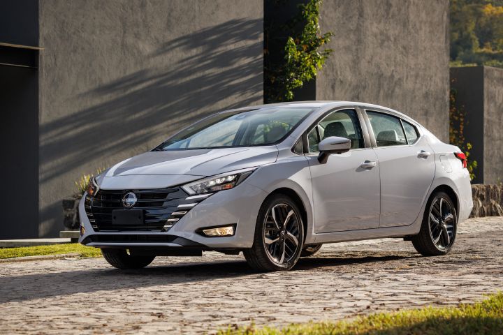 Nissan Versa gris en fondo gris con plantas verdes