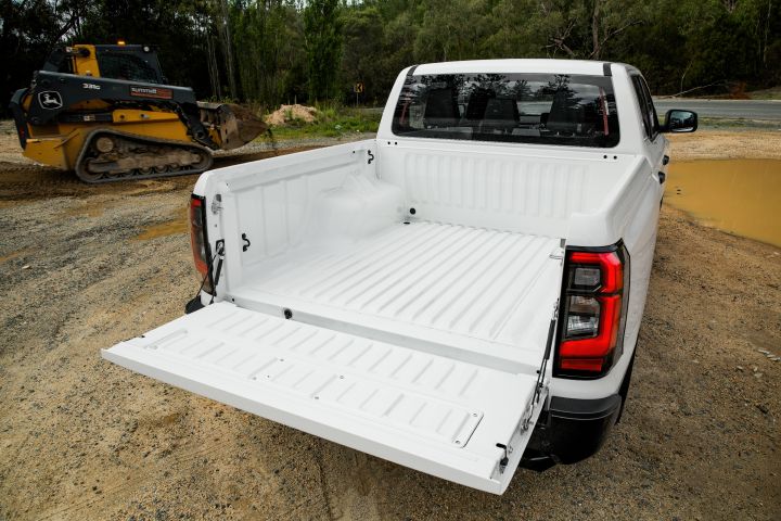 2026 Nissan Navara SL dual cab ute finished in Alpine White photographed from the rear three-quarter angle with the tailgate lowered, revealing the cargo tub and tray interior