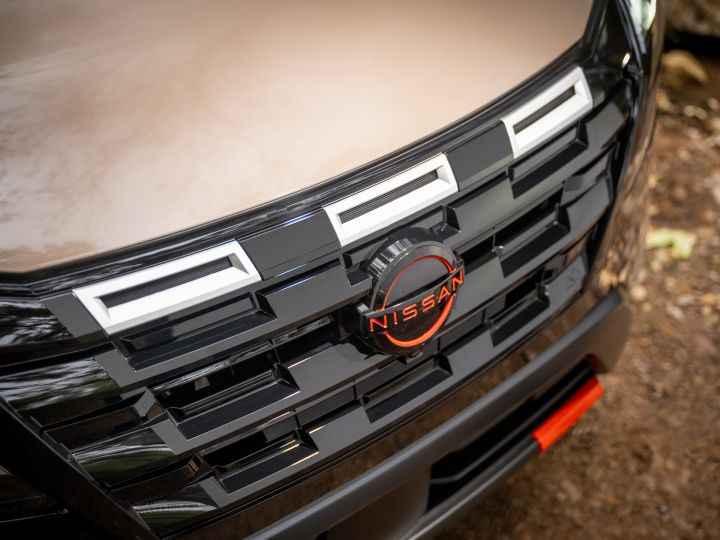 Close up of the black grill on a tan 2025 Nissan Rogue rock creek, the Nissan emblem is red.