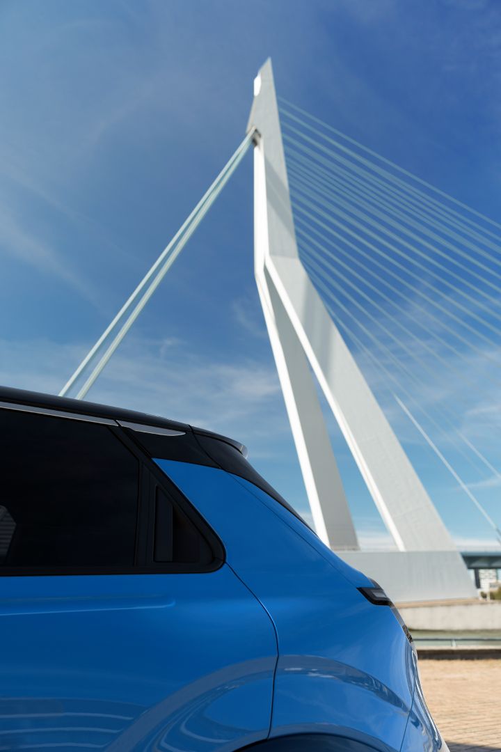 Detailansicht der seitlichen Heckpartie eines blauen Nissan Micra, im Hintergrund sieht man eine hohe weiße Brücke