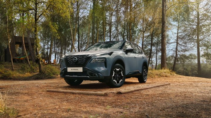 Ceremic Grey Nissan X-Trial N-Trek voorzijde 3/4 links in een bosrijke omgeving