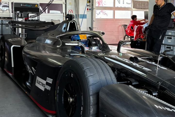 Zane Maloney sitting in the Nissan Formula E Team GEN4 car in the garage with his blue and yellow helmet visible.