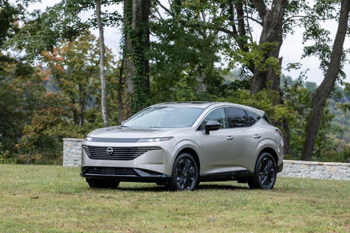 A silver 2025 Nissan Murano parked on grass, trees are behind.