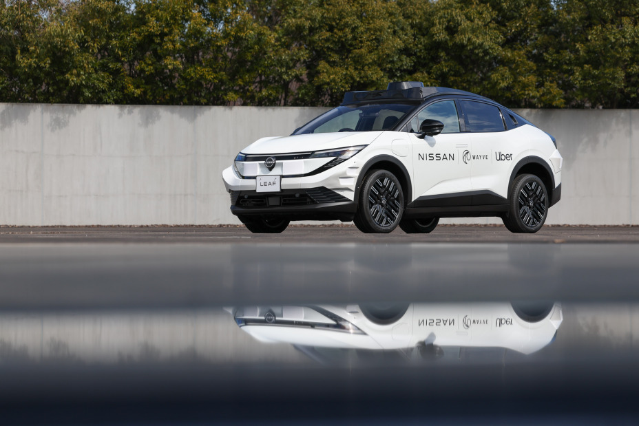 Nissan LEAF branco com o teto preto traz acima do teto radares que possibilitam o uso sem motorista. Na lateral, traz as logomarcas de Nissan, Wayve e Uber