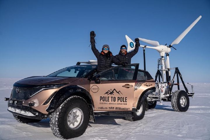 Casal de aventureiros fazendo pose dentro de um Nissan Ariya parado com as portas abertas em um cenário com neve.